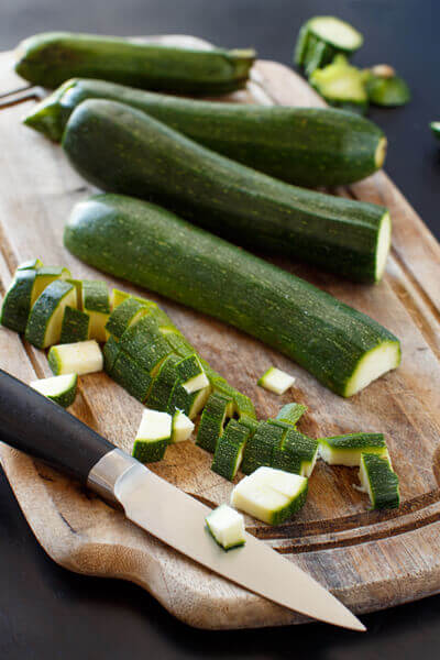 chopped zucchinis on cutting board with knife